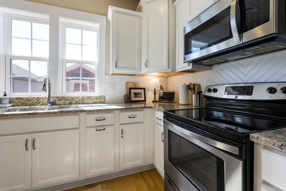 Bright and stylish modern kitchen featuring white cabinets and granite countertops with stainless steel appliances.