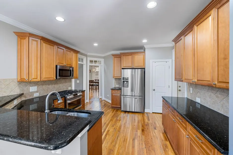 Spacious modern kitchen featuring granite countertops, wooden cabinets, and stainless steel appliances.